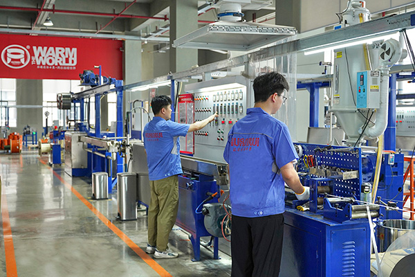 工人在操作電伴熱帶護(hù)套擠出設(shè)備。 環(huán)瑞電熱供圖